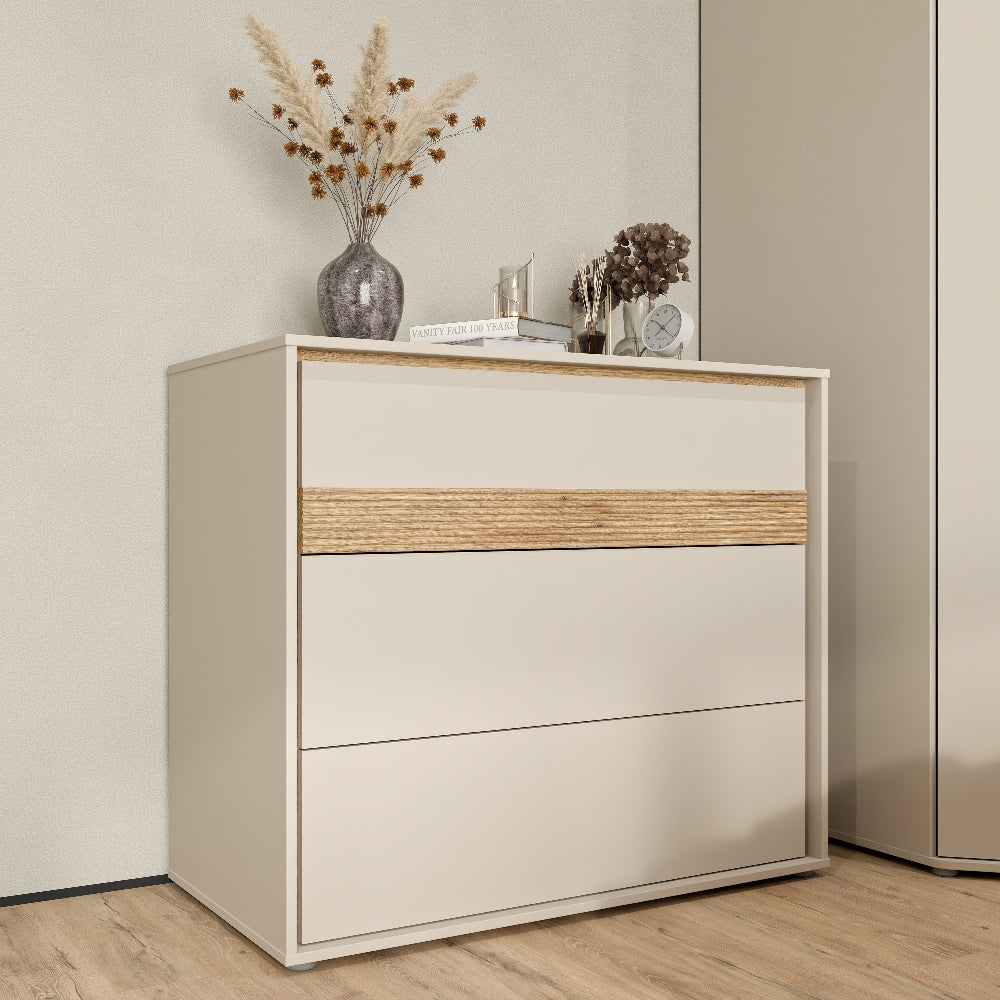 Komoda Wexlin smėlio spalvos su Mauvella ąžuolo detalėmis – modernus ir talpus miegamojo baldas.